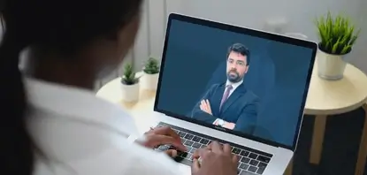 Mulher preta com um notebook no colo enquanto assiste uma aula do Curso de Formação para Advogados